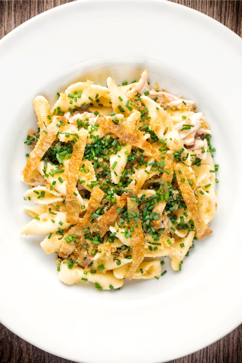 Portrait over head image of sage and onion chicken pasta served in a white bowl