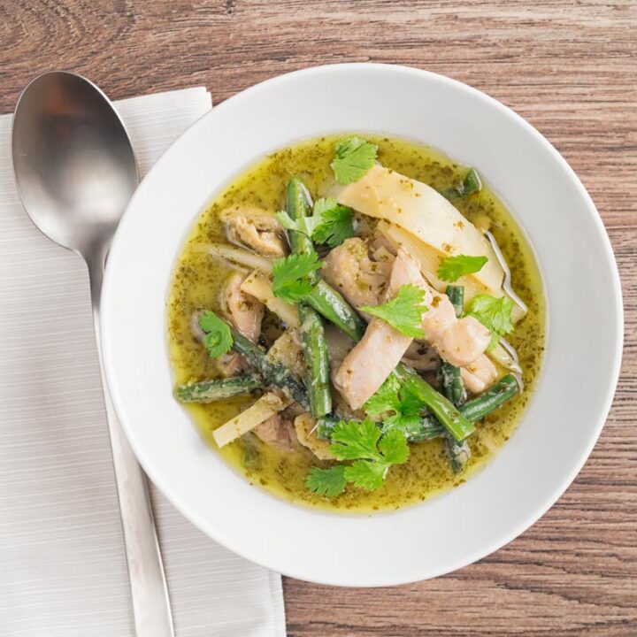 Square overhead image of Thai Green Chicken Curry featuring green beans and bamboo shoots served in a white bowl