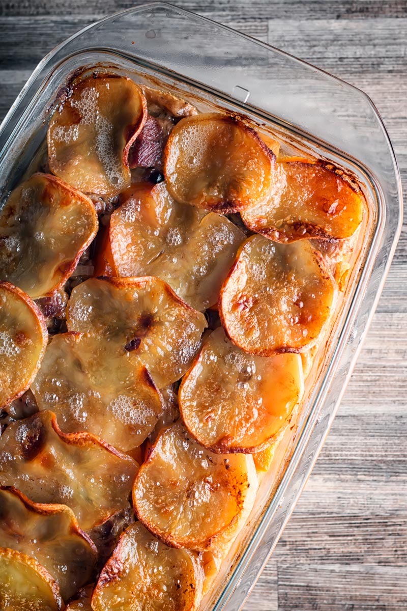 Overhead portrait image of a lamb hotpot pie with a lid of sliced golden potatoes