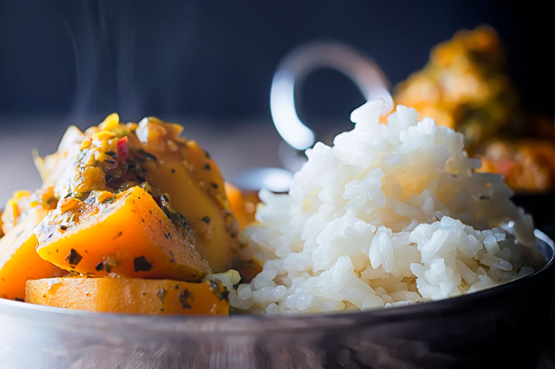 Landscape close up image of a pumpkin curry served with white rice