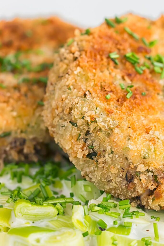 Portrait close up image of golden sardine and salmon fishcakes served on creamed leaks