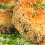 Portrait image of golden sardine and salmon fishcakes served on creamed leeks with text overlay