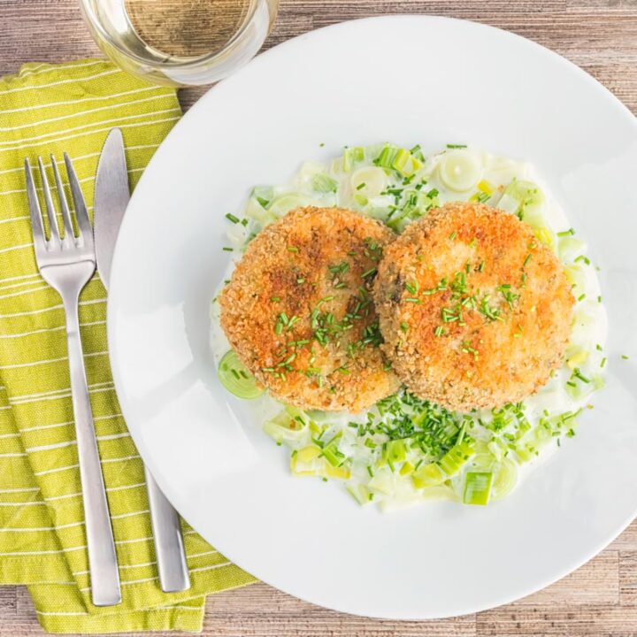 Square overhead image of golden sardine and salmon fishcakes served on creamed leeks