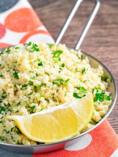 Portrait image of a herby buttered couscous served with a lemon wedge