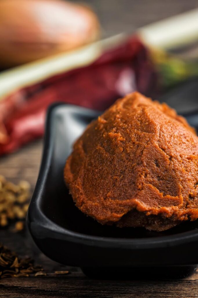 Portrait close up image of a homemade massaman curry paste surrounded by ingredients