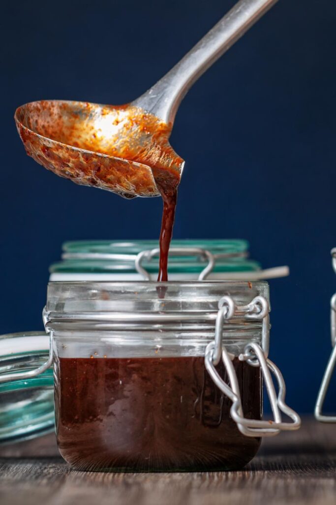 Portrait image of homemade Chinese plum sauce being decanted into storage jars