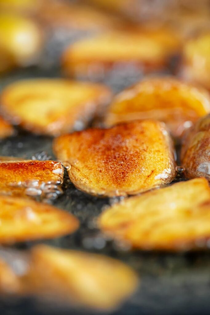 Portrait image of golden fried potatoes being shallow fried in oil