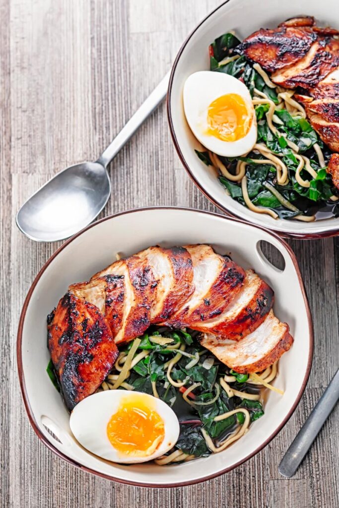 Portrait overhead image of a hoisin chicken ramen with a boiled egg and Swiss chard