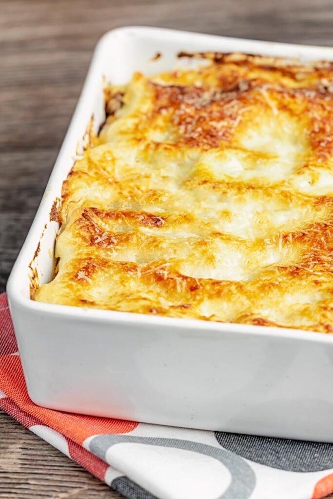 Portrait image of a classic Lasagna Bolognese in an oven proof white baking dish