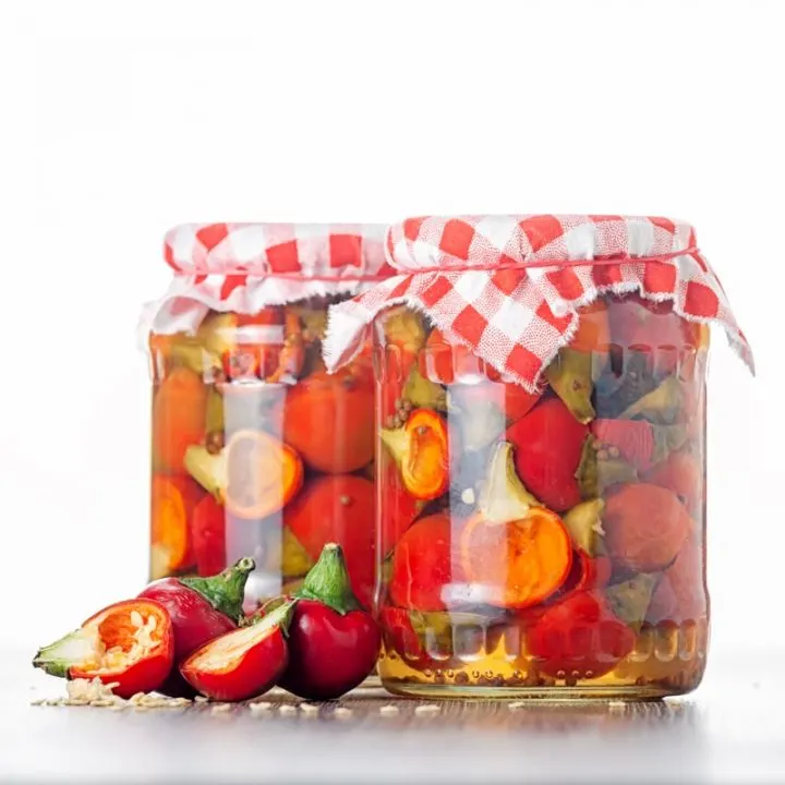 Square image of jars of pickled cherries with halved and deseeded cherry bomb chillies