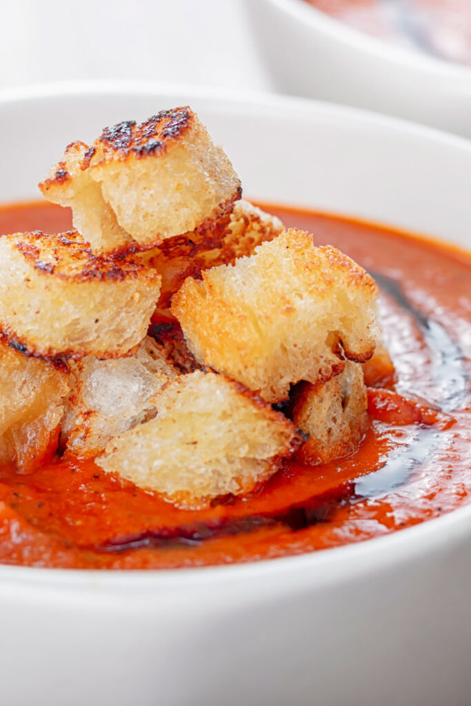 Portrait image of a tower of toasted croutons served with tomato soup