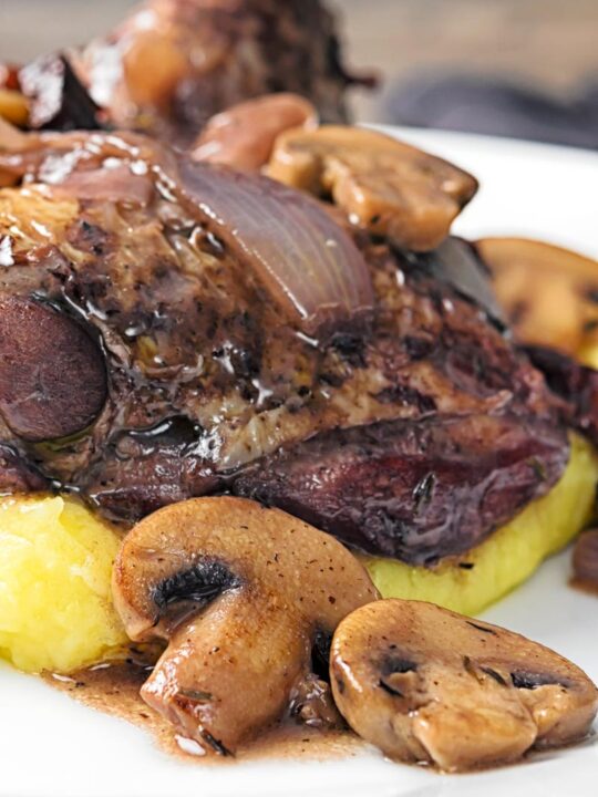 Portrait close up image chicken in a red wine sauce with mushrooms and bacon served on mashed potato