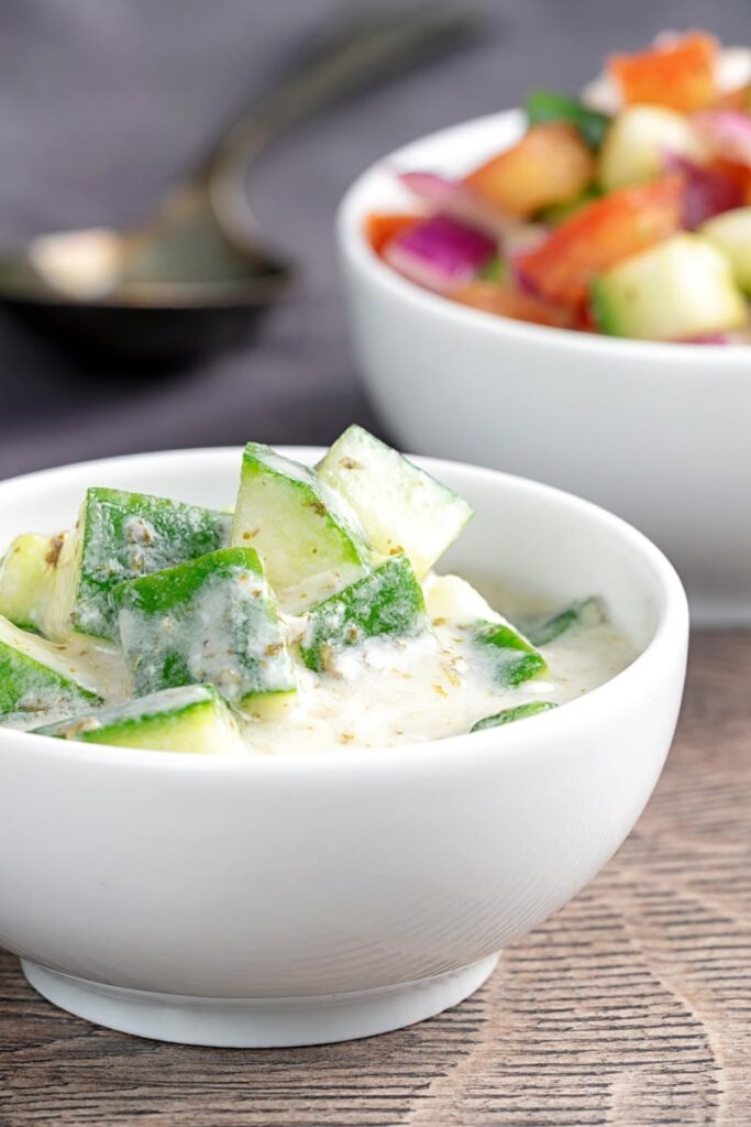 Portrait image of a cucumber and mint raita served in a small white bowl.