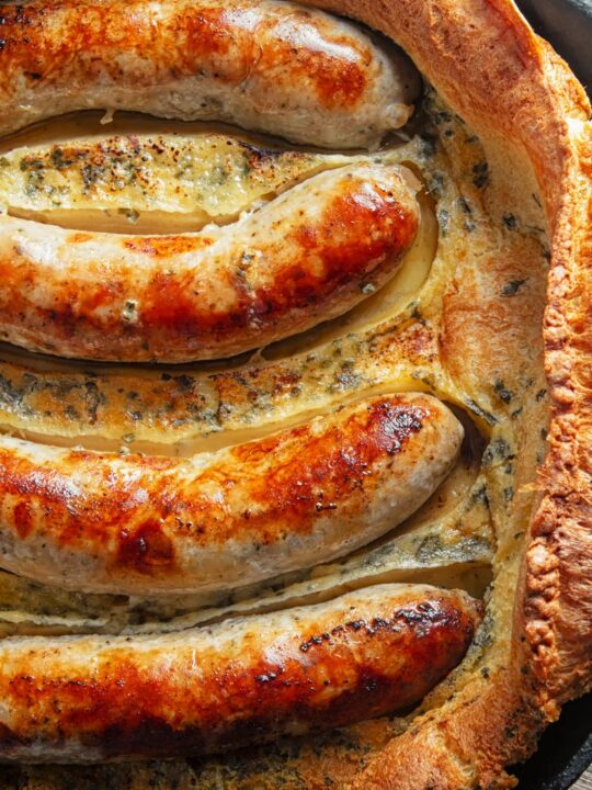 Portrait close up overhead image of toad in the hole, or sausages cooked in a Yorkshire pudding batter