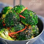 Portrait image of stir fry broccoli featuring sesame seeds, ginger and red pepper served in a mini wok with text overlay