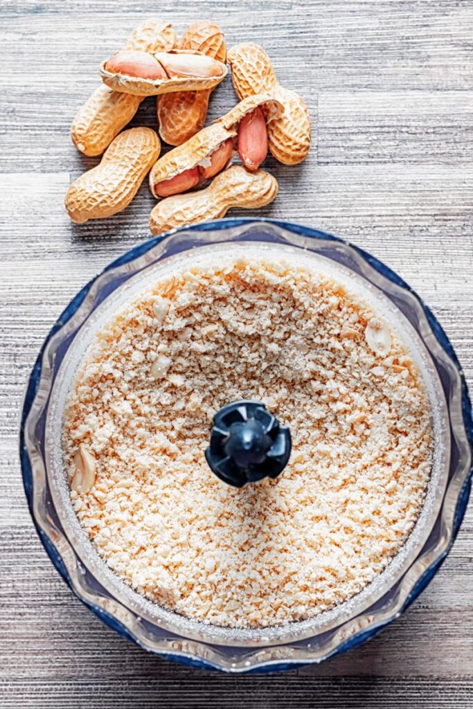 Portrait image of homemade peanut butter being made in a mini blender at the powdery phase
