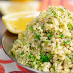 Portrait image of perfectly cooked bulgur wheat with fresh parsley and lemon wedges