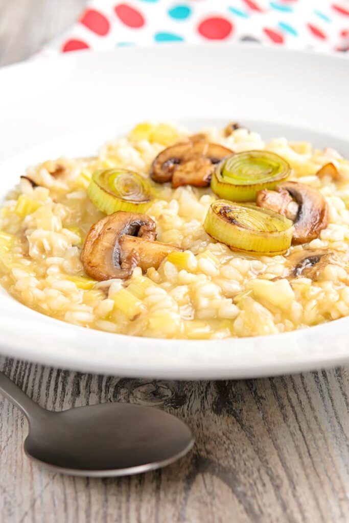 Portrait close up image of a leek and mushroom risotto served in a white bowl