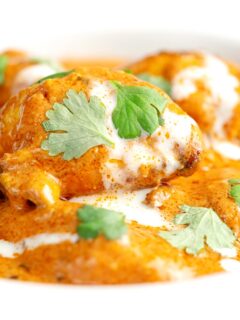 Portrait close up image of murgh makhani or a butter chicken curry with a swirl of cream and fresh coriander