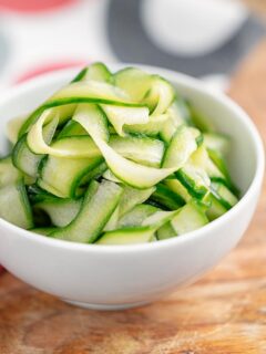 Portrait image of quick pickled cucumber ribbons served in a white bowl