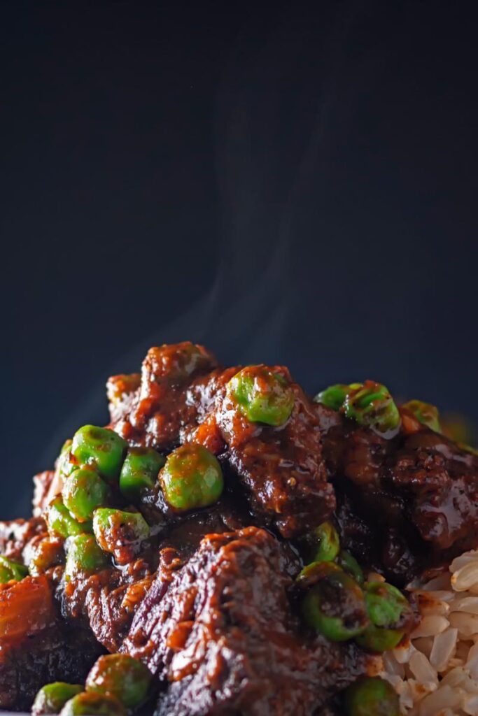 Portrait close up image of a steaming hot rich beef curry with peas