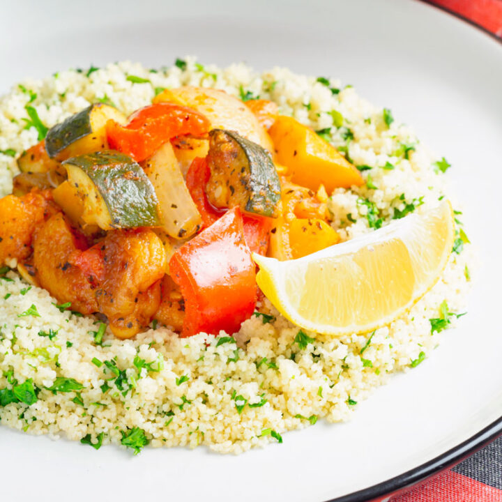 Square overhead image of a vegetarian Moroccan influence vegetable tagine served on a bed of herbed couscous