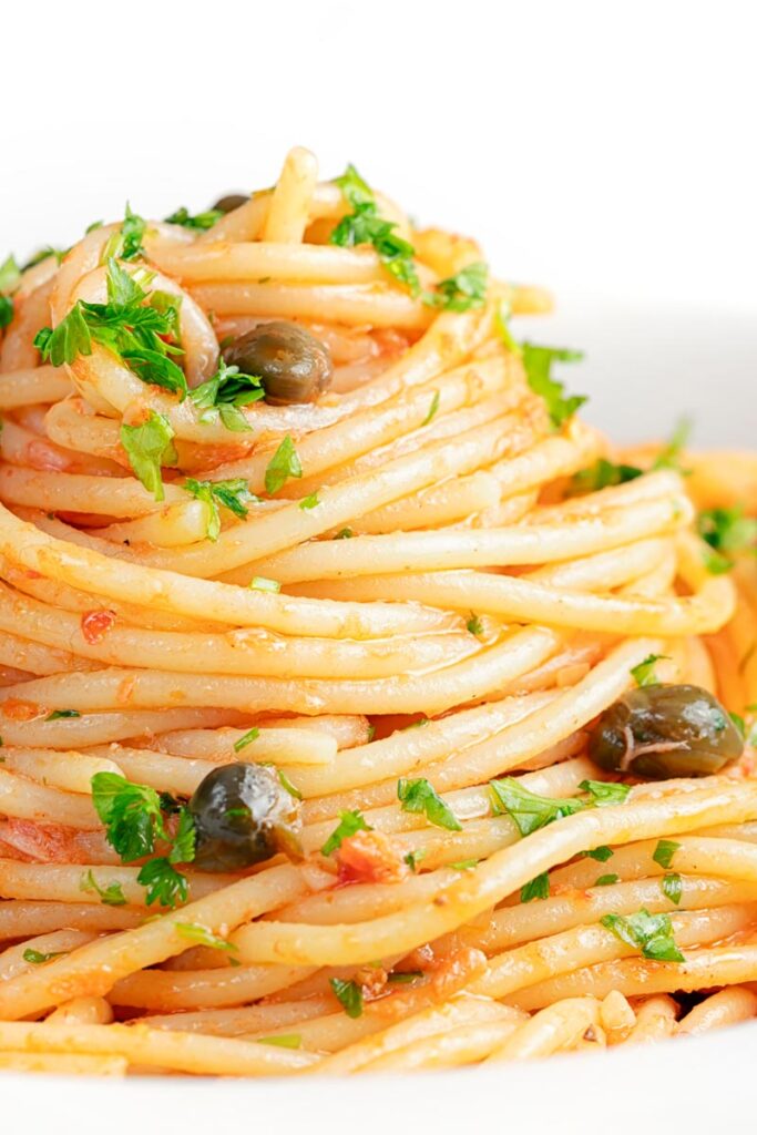 Portrait close up image of a pile caper, tomato and tuna spaghetti