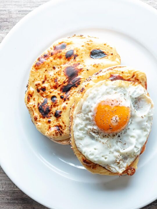 Portrait overhead image of welsh rarebit with a fried egg, AKA buck rarebit served on a white plate