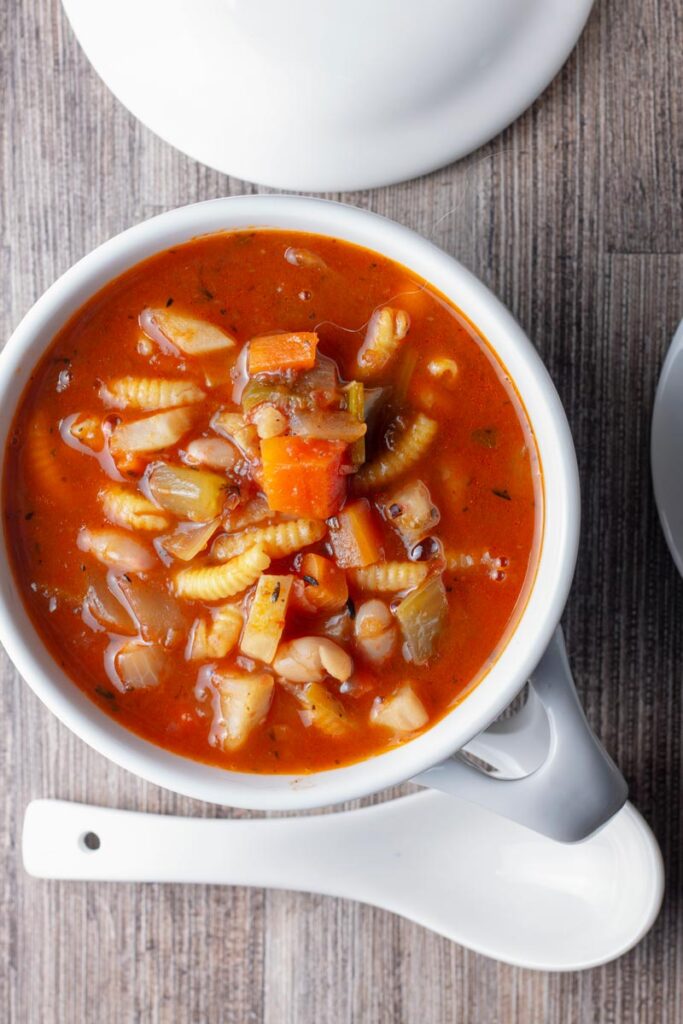 Portrait overhead image of a winter vegetable soup served in a white cup