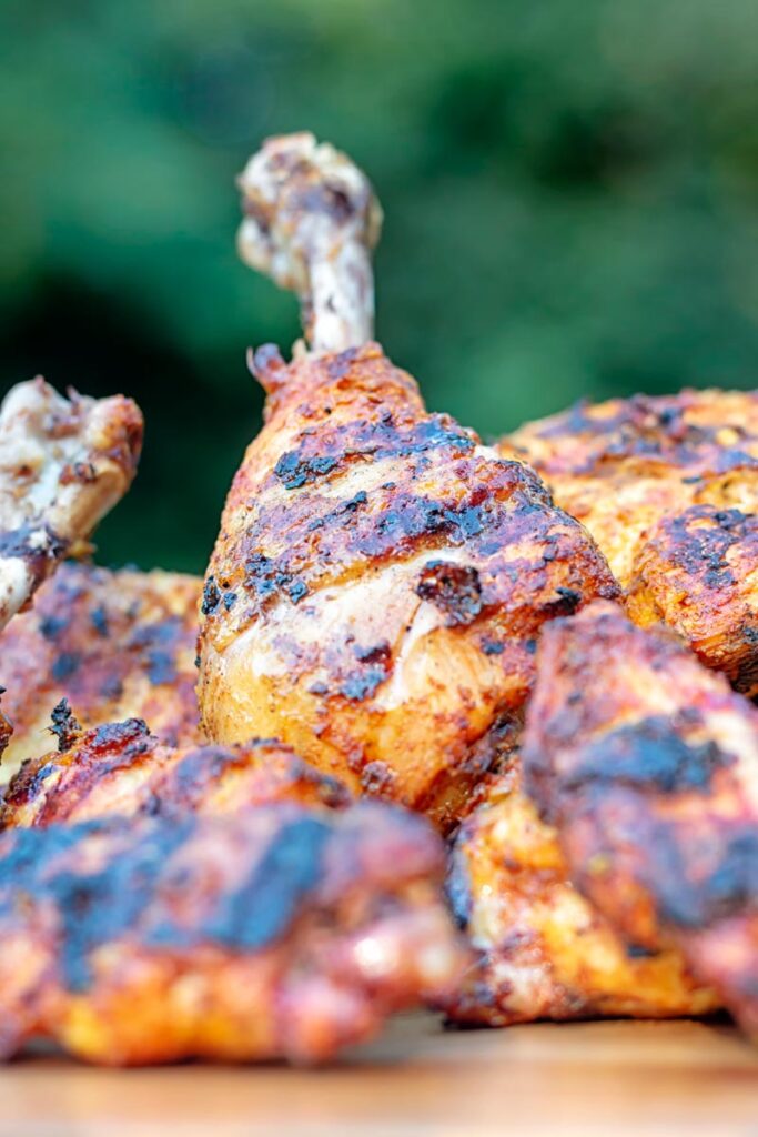 Portrait close up image of a BBQ tandoori chicken drumstick with surrounded by out of focus chicken