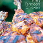 Portrait close up image of a BBQ tandoori chicken drumstick with surrounded by out of focus chicken with text overlay