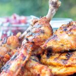 Portrait image of a BBQ tandoori chicken drumstick with surrounded by out of focus chicken