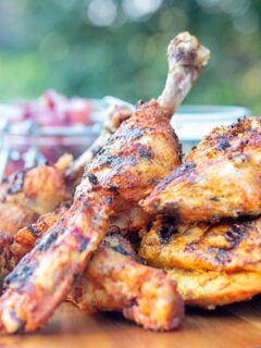 Portrait image of a BBQ tandoori chicken drumstick with surrounded by out of focus chicken