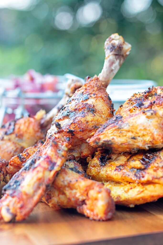 Portrait image of a BBQ tandoori chicken drumstick with surrounded by out of focus chicken