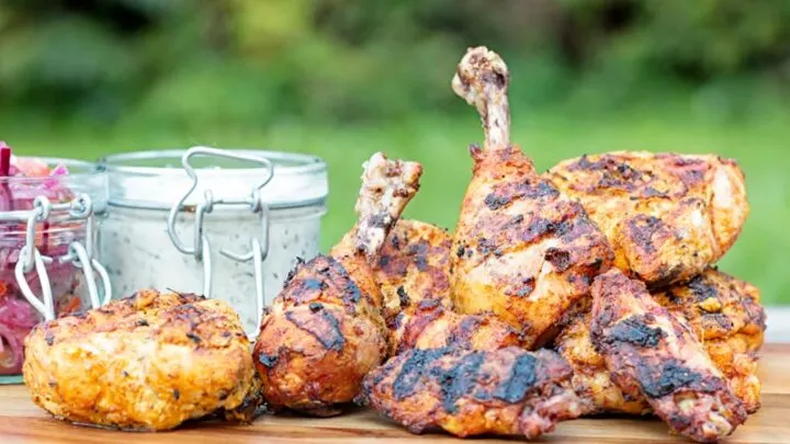 Landscape image of a tandoori chicken served with raita and onion salad