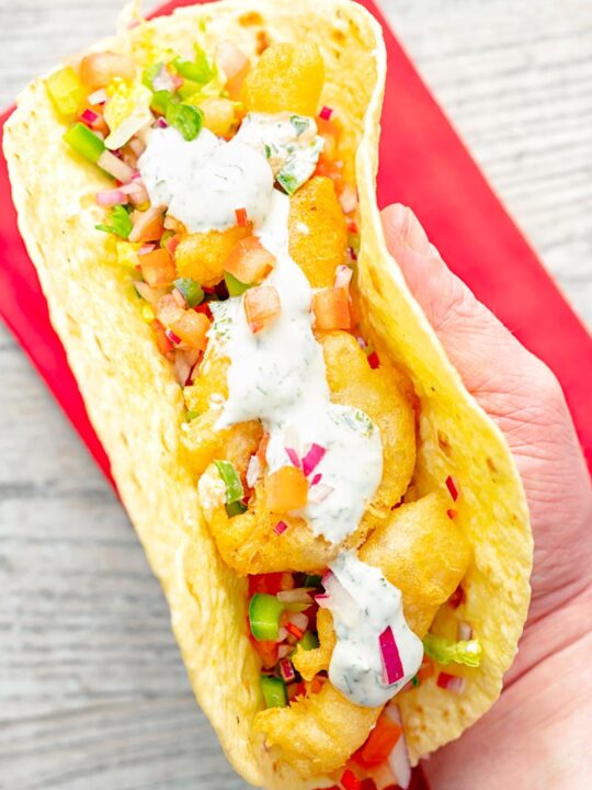 Portrait overhead image of beer battered cod fish tacos served in a corn tortilla with a coriander crema