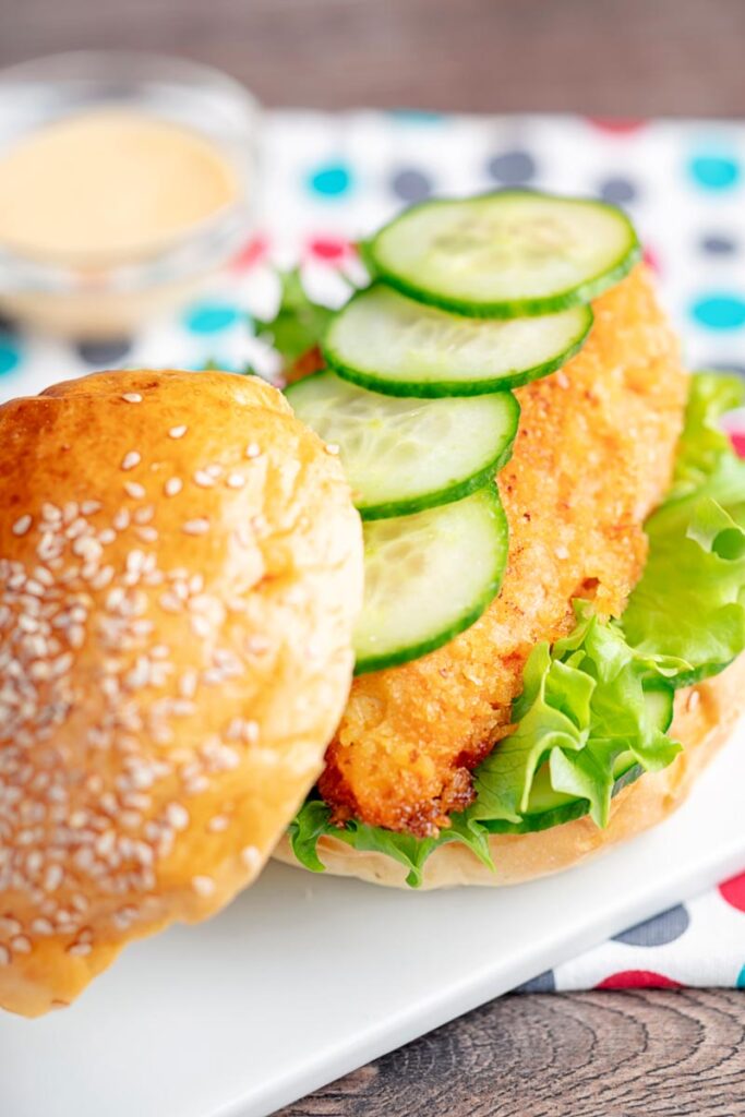 Portrait image of a chicken breast burger with lettuce and cucumber