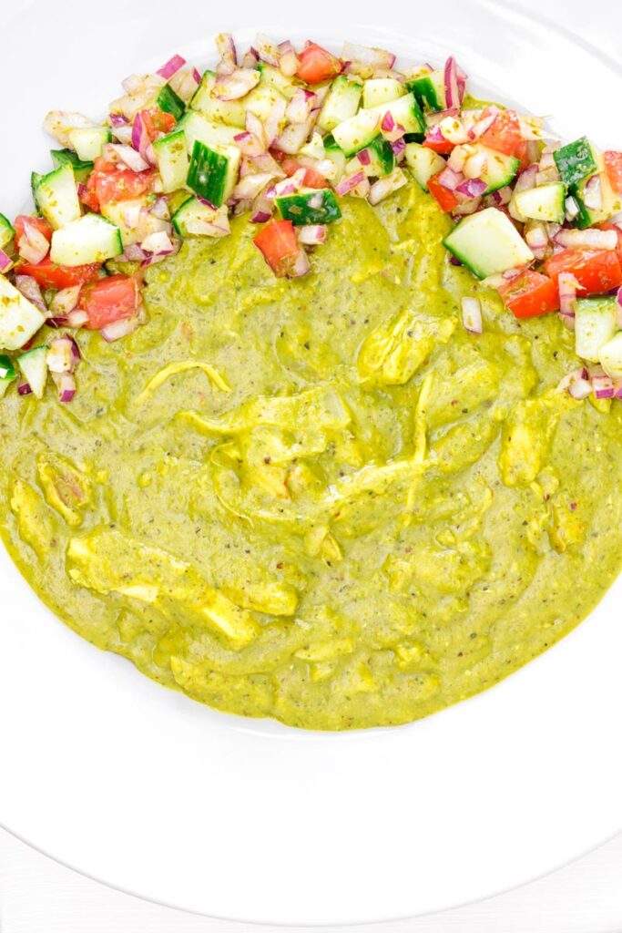 Portrait overhead image of a chicken dhansak curry served with kachumber salad in a white bowl