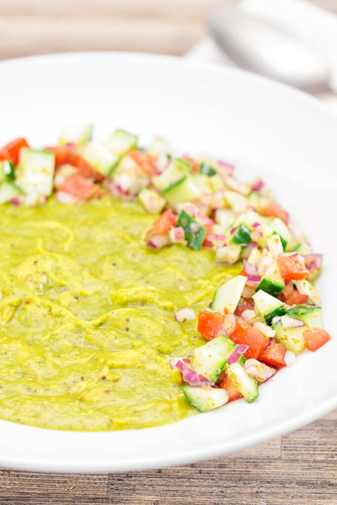 Portrait image of a chicken dhansak curry served with kachumber salad in a white bowl