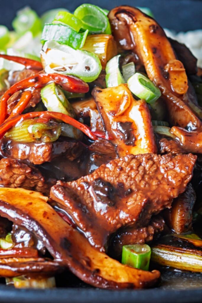 Portrait close up image of a streaming hot Chinese beef and shiitake mushroom stir fry