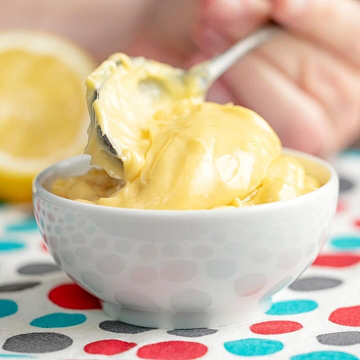 Square image of thick classic homemade mayonnaise being served into a white bowl