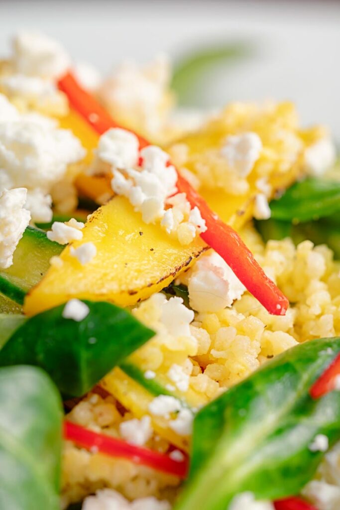 Portrait close up image of a main course mango salad featuring lambs lettuce with feta cheese, millet and chilli shreds