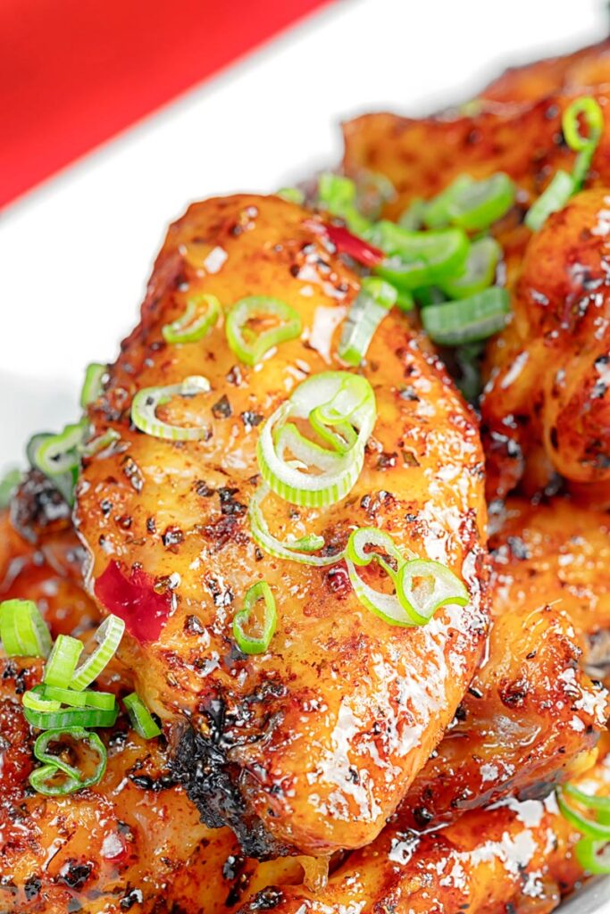 Portrait close up image of sticky glazed Thai Chicken wings with shredded spring onion