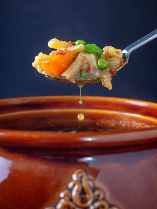 Portrait image of a spoon or soupe au pistou taken from a a bowl with a drip of broth