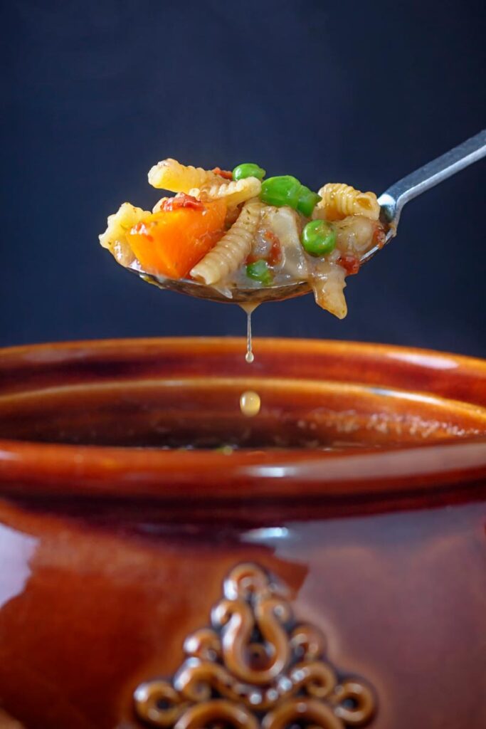 Portrait image of a spoon or soupe au pistou taken from a a bowl with a drip of broth