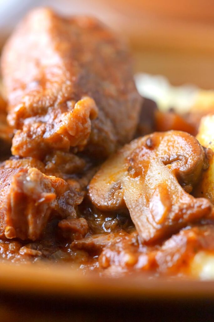 Portrait close up image of a tomato based wild boar stew with mushrooms