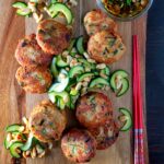 Portrait overhead image of spicy Thai tuna fish cakes served with a cucumber and peanut salad and a dipping sauce.