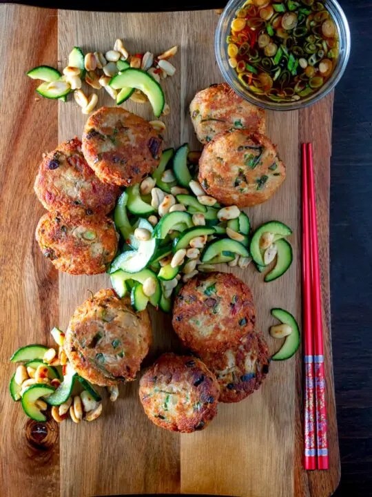 Portrait overhead image of spicy Thai tuna fish cakes served with a cucumber and peanut salad and a dipping sauce.