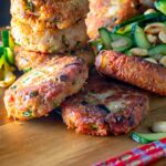 Portrait image of spicy Thai tuna fish cakes served with a cucumber and peanut salad