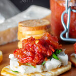 Portrait image of a tomato and chilli jam served with cheese and crackers with text overlay